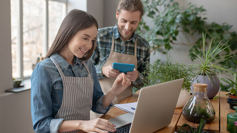 A man with a tablet and a woman with a laptop in a shop