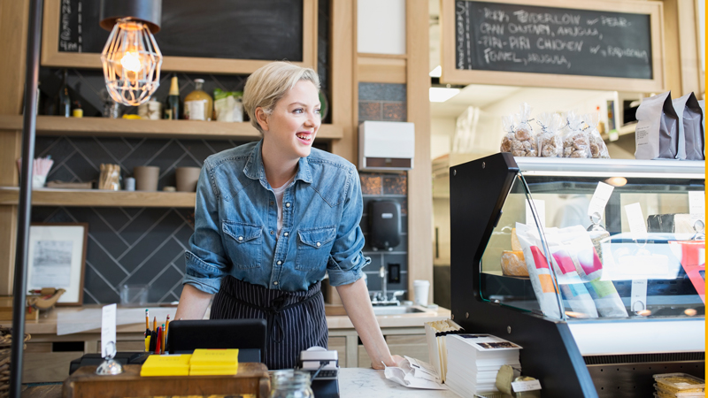 542091377 Retailer behind front counter in her shop.