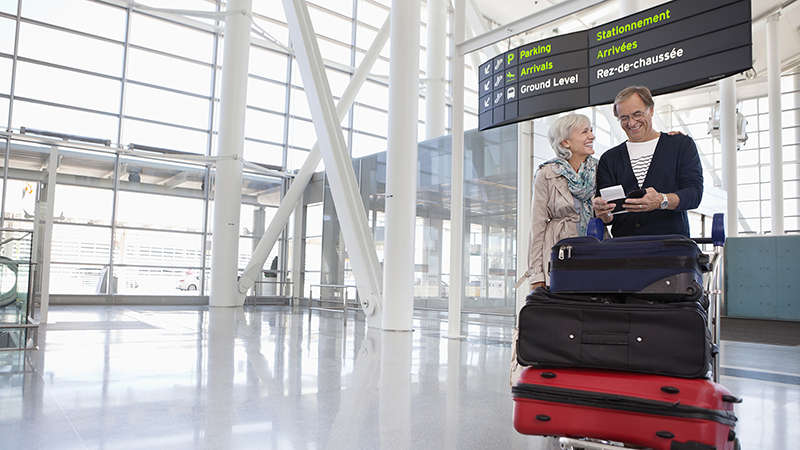 Senior couple with luggage at airport Smiling couple with full luggage trolley in airport.