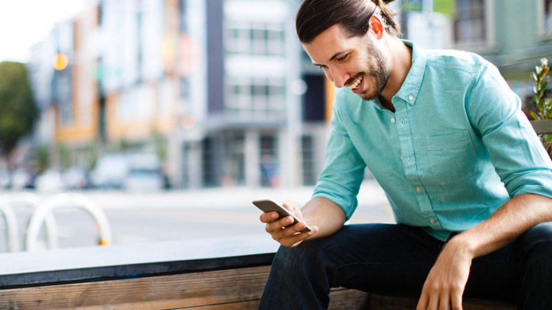 A man with a smartphone sitting outside